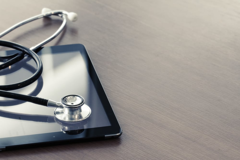 Studio macro of a stethoscope and digital tablet with shallow DOF evenly matched abstract on wood table background copy space